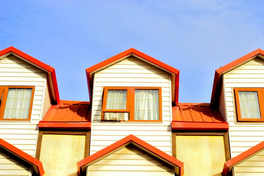 Low angle view of townhouses with red roofs and white facades against a clear blue sky.
