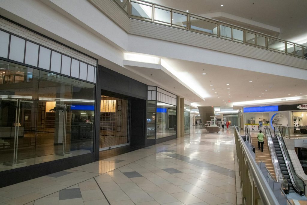 Spacious and contemporary mall interior with closed stores and escalator.